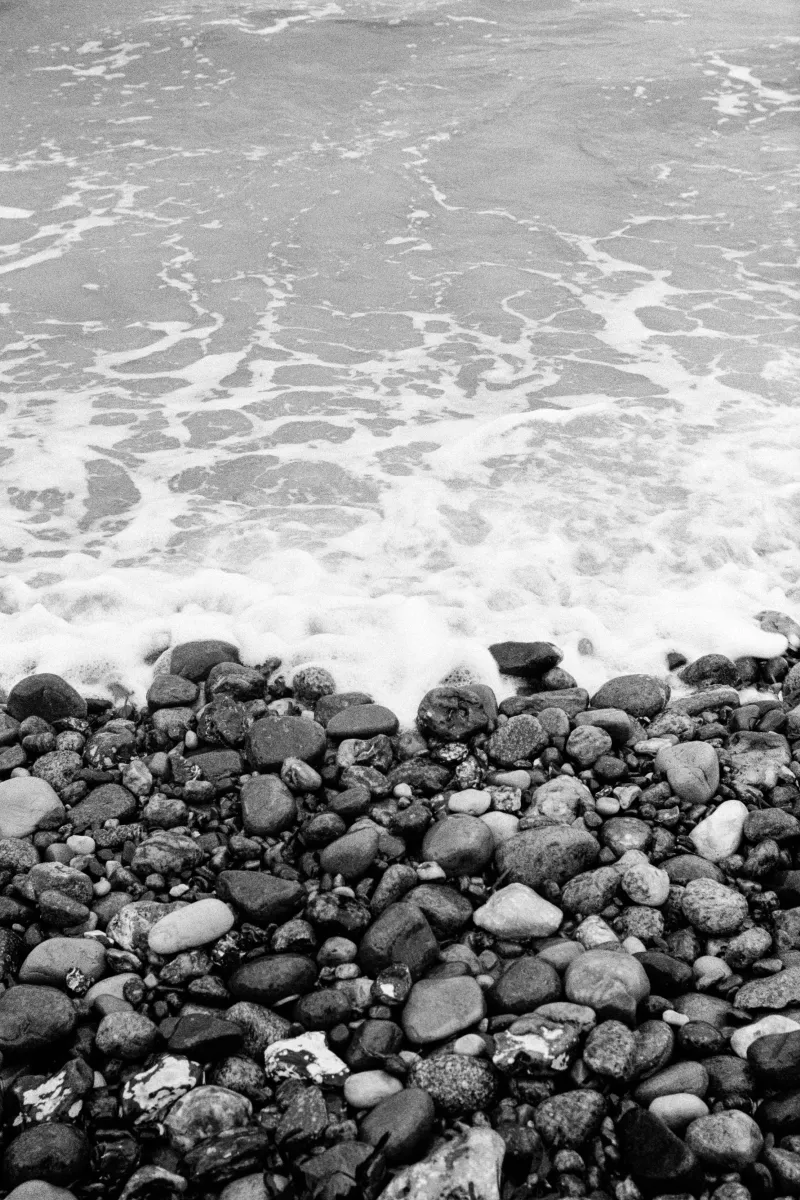 Foaming ocean waves washing over pebble beach shore