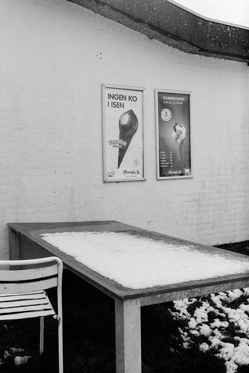 Danish ice cream posters on wall above snow-covered outdoor table