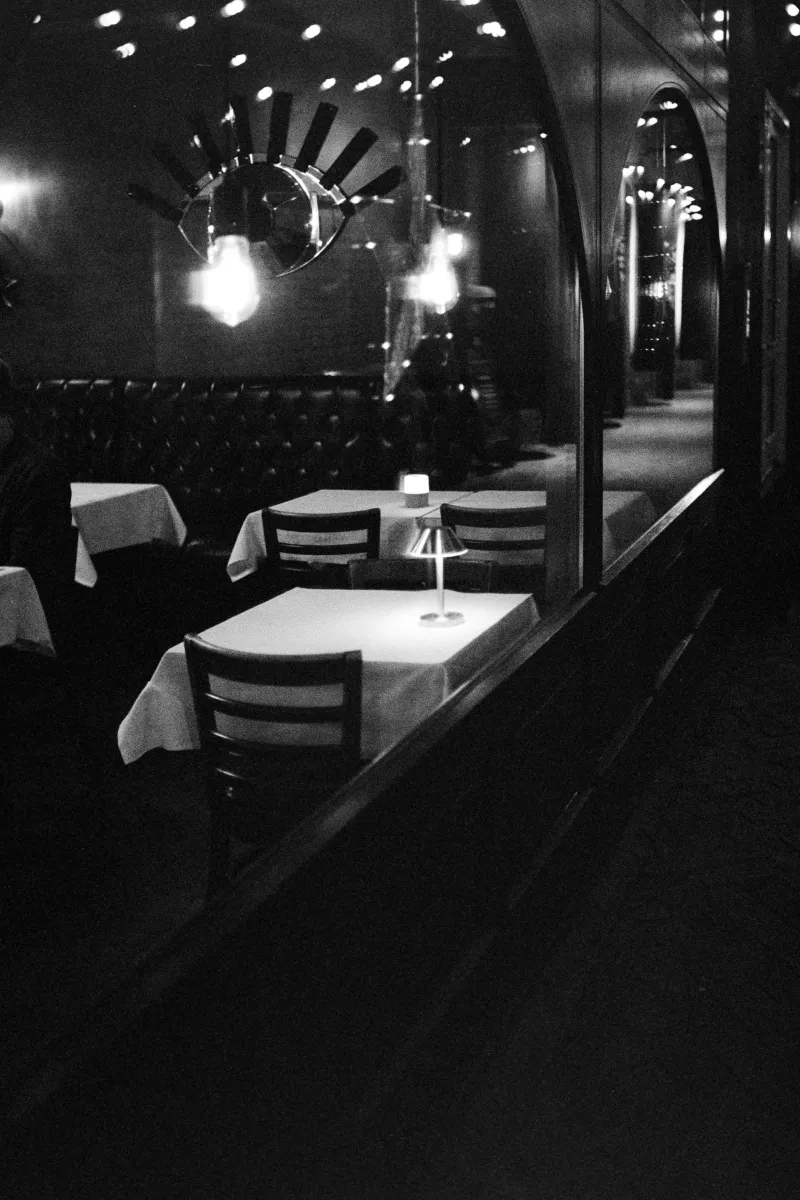Classic restaurant interior photographed through window with eye-shaped mirror and modern pendant lights