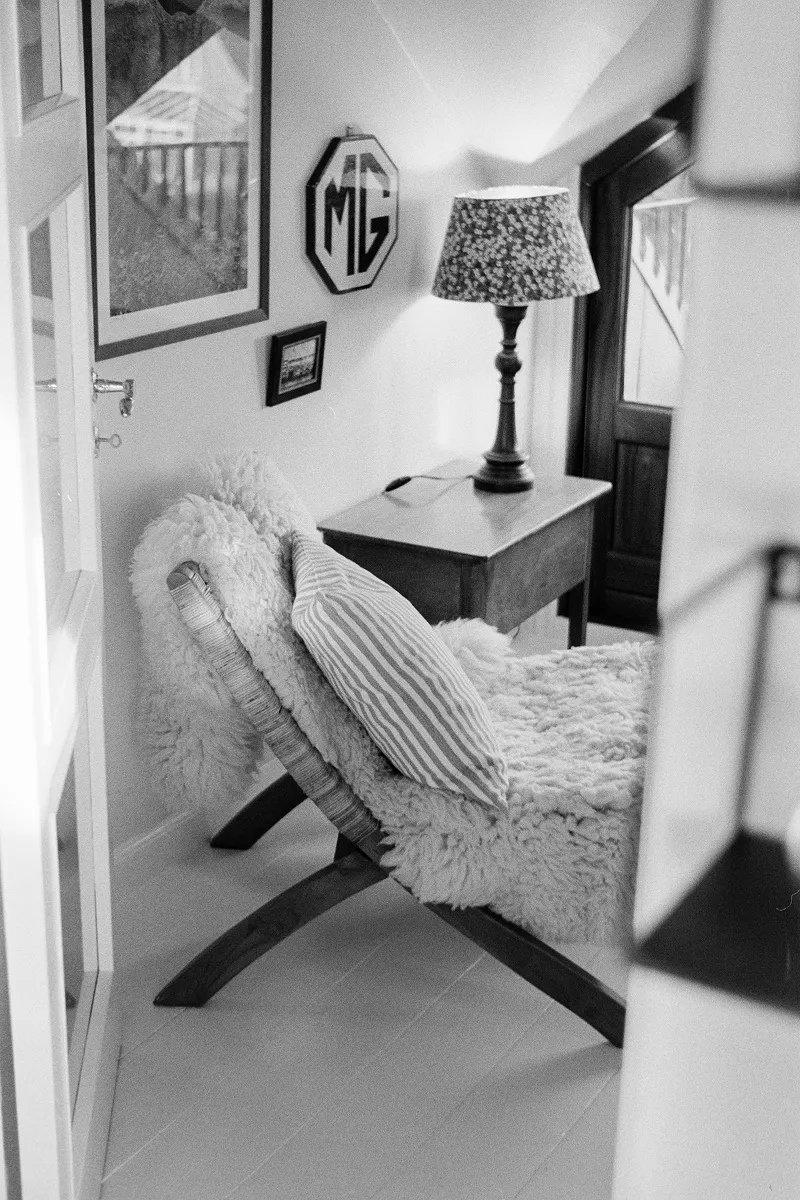 Cozy apartment corner photographed from kitchen doorway with sheepskin bench and vintage MG sign