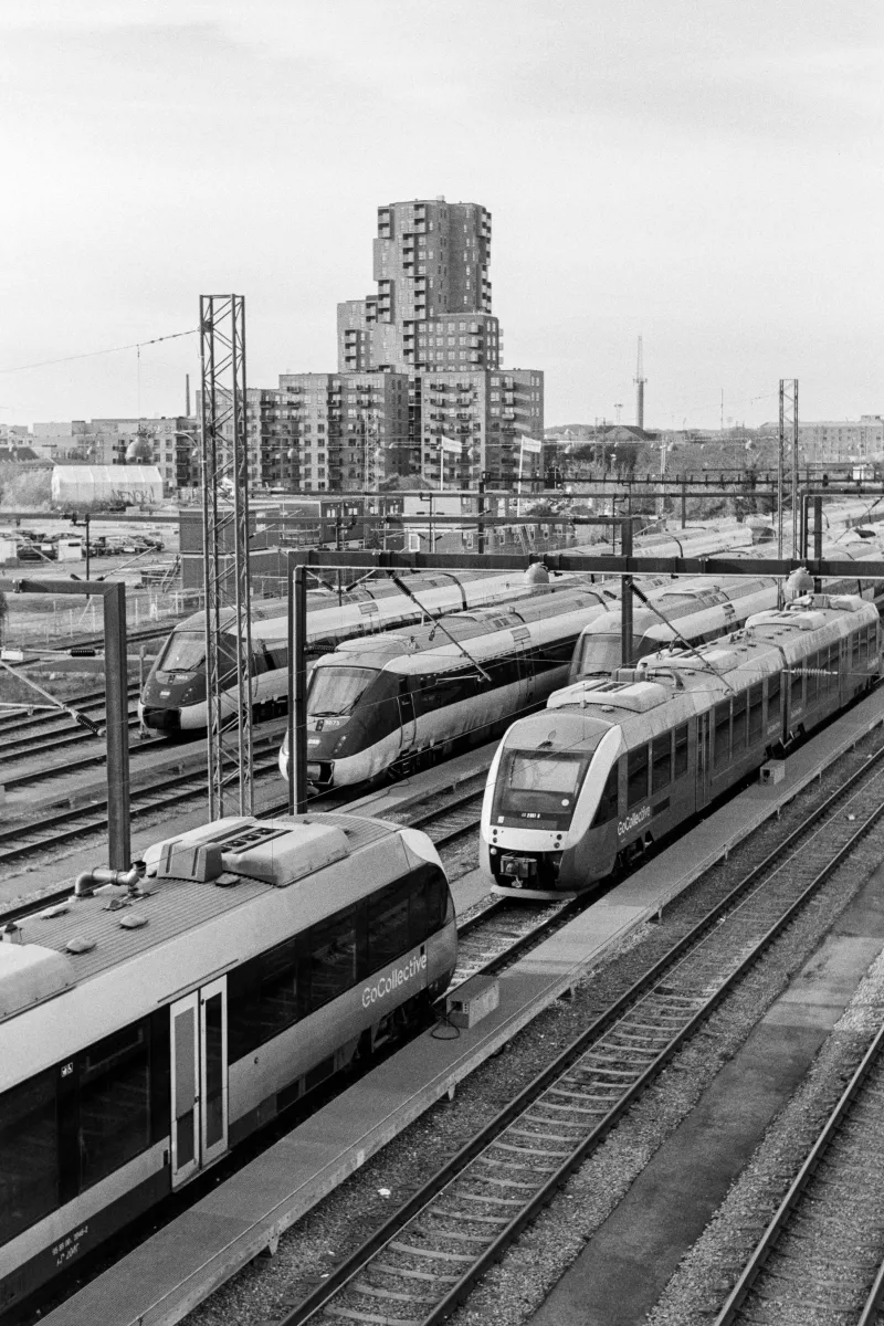 Multiple passenger trains at railway station with modern residential tower in background