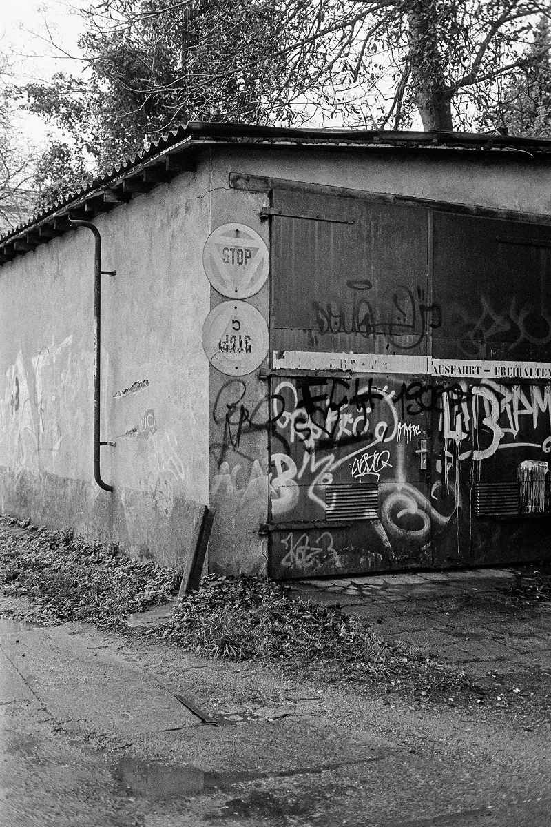 An old garage with signs and a spray-painted garage door.