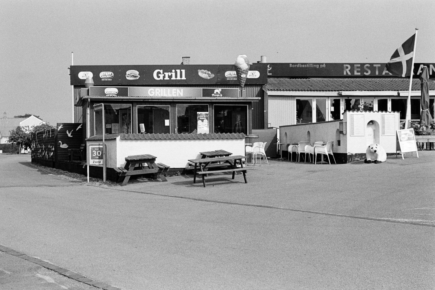 Grill restaurant with Danish flag and outdoor seating area with picnic tables