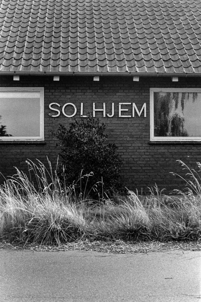 Brick house facade with SOLHJEM lettering between two windows and tiled roof