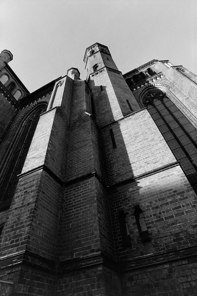 Low-angle B&W shot of the towering brick facade and spires of the St. Paul's Church, emphasizing dramatic height.